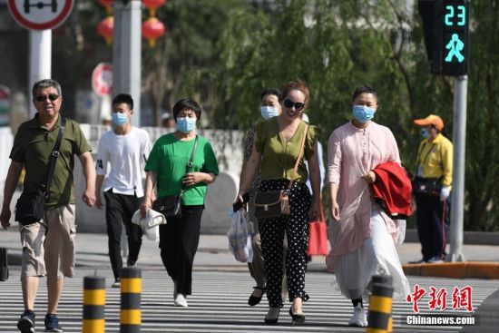 6月6日，北京市门头沟区，市民在一处十字路口过马路。当日0时起，北京市突发公共卫生事件应急响应级别由二级调至三级，并相应调整防控策略。中新社记者