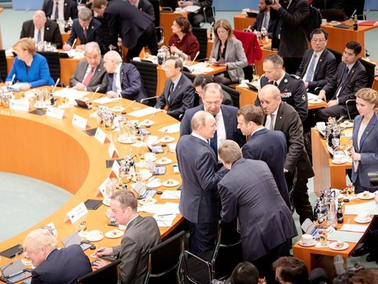 1月19日，利比亚问题国际会议上，俄罗斯总统普京与法国总统马克龙交谈。（Reuters）